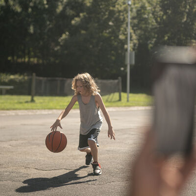 Ein Kind spielt mit einem Basketball auf der Spielfl&auml;che an der Mainl&auml;nde.