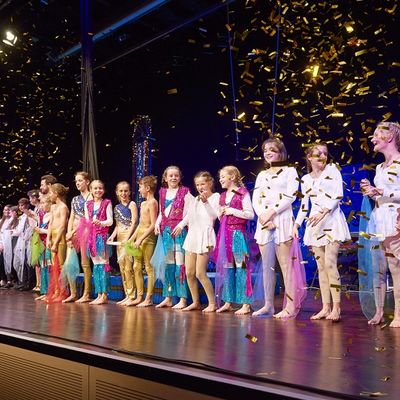 Eine Gruppe bunt gekleideter Kinder steht auf der Bühne.