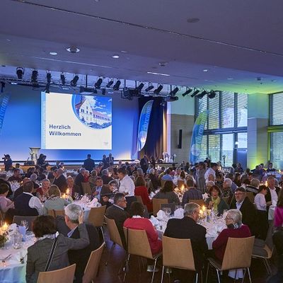 Die Besucher der Ehrenamtsgala sitzen zusammen an Tischen und schauen auf die B&uuml;hne.