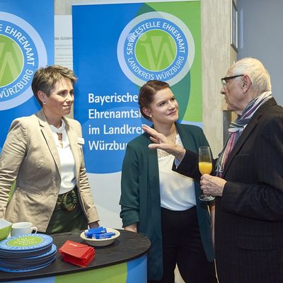 Ein Besucher unterh&auml;lt sich mit zwei Mitarbeiterinnen des Landratsamts an einem Stand.