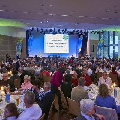 G&auml;ste der Ehrenamtsgala sitzen zusammen an runden Tischen in einem Saal.