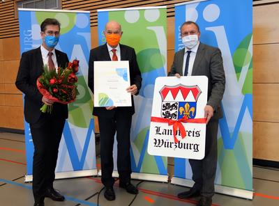 Aus Landrat a.D. Eberhard Nu&szlig; wurde mit der Aush&auml;ndigung der Urkunde w&auml;hrend der Kreistagssitzung in Bergtheim Altlandrat Eberhard Nu&szlig;. Zu diesem Ehrentitel gratulierten Landrat Thomas Eberth (r.) und Oberb&uuml;rgermeister Christian Schuchardt. 