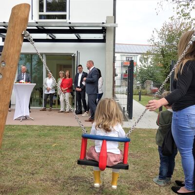 Ein Kind sitzt auf einer Schaukel bei der Er&ouml;ffnungsveranstaltung der Kita des Landratsamtes W&uuml;rzburg.