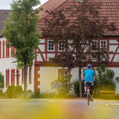 Ein Fachwerkhaus in Retzstadt. Auf der Straße davor fährt ein Radfahrer.